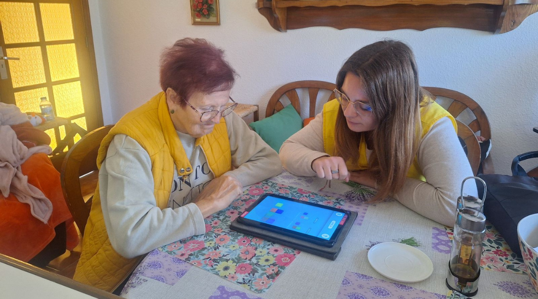 SPAPD Una trabajadora de una residencia ayuda a una mujer mayor a usar una tableta.